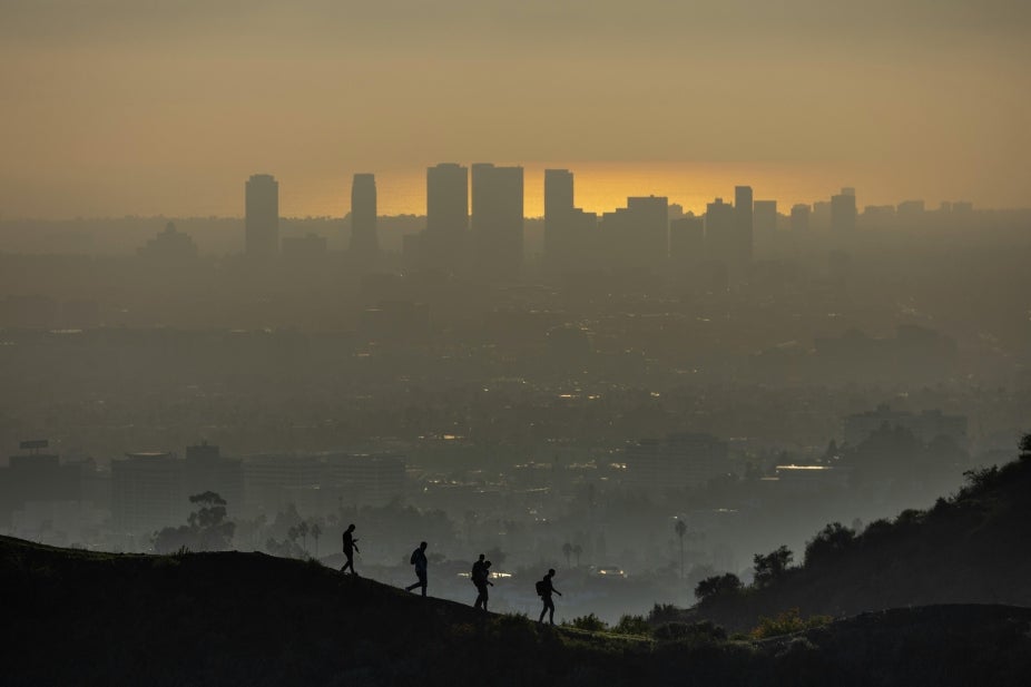 Hikers silhouetted against a smoggy city skyline