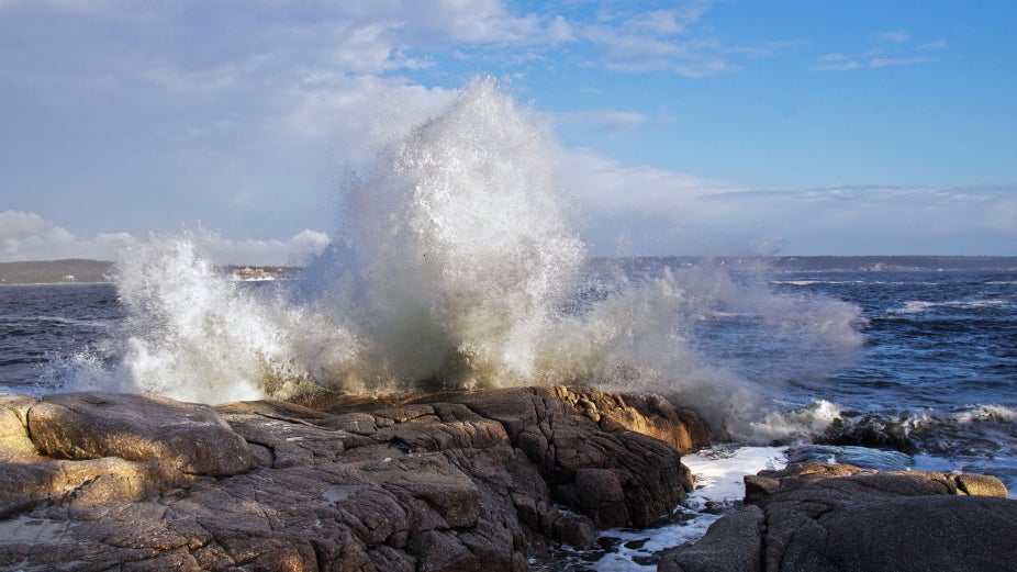 An ocean wave crashes over rocks
