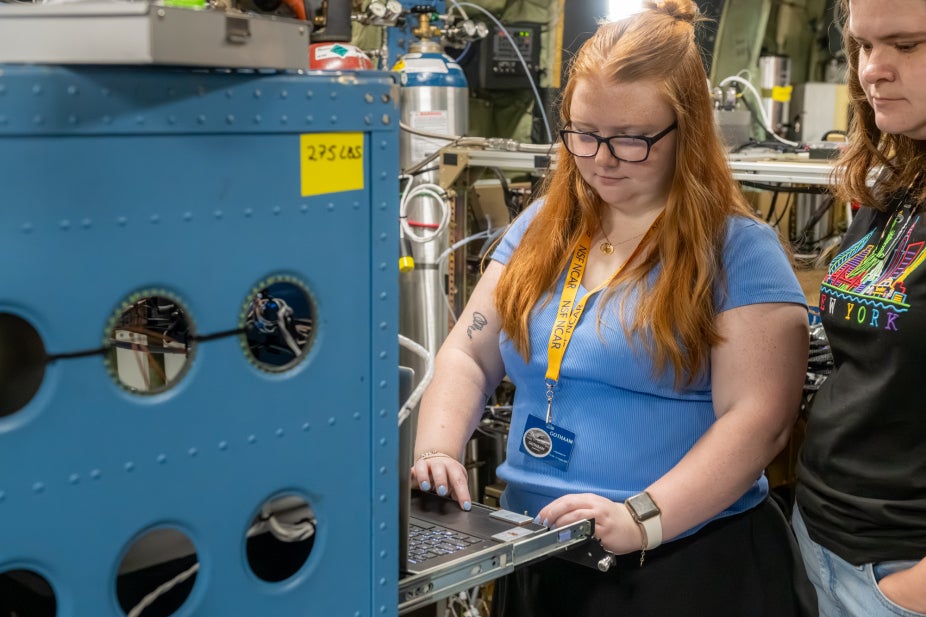 Scientists stand at an instrument rack inside the NSF NCAR C-130
