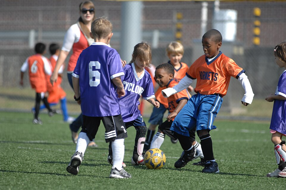 Children play soccer on a field.