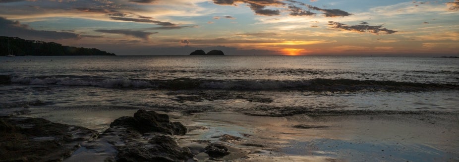 Sunset over a beach, rocky shore, and ocean