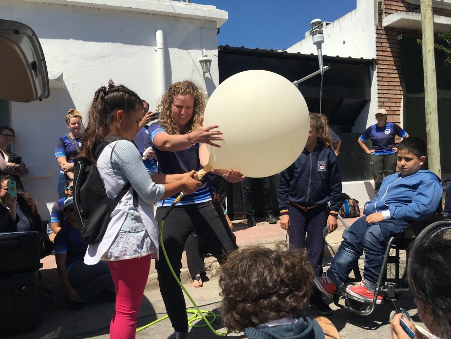 un científico trabaja con jóvenes estudiantes en Argentina para preparar un globo meteorológico para su lanzamiento