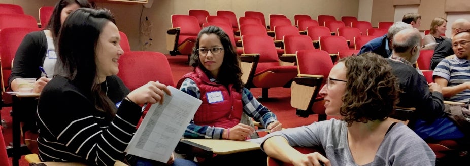 Picture of postdocs in a meeting room talking to each other.