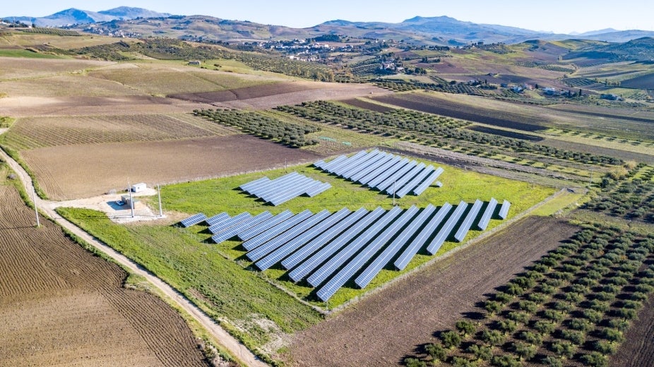 Photovoltaic plant, or solar panels on an Italian hillside near agriculture and homes.