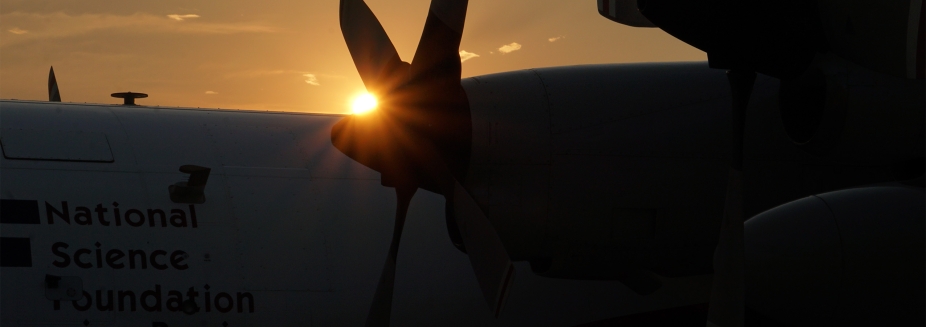 A closeup of the propeller of a research aircraft, backlit by a setting sun