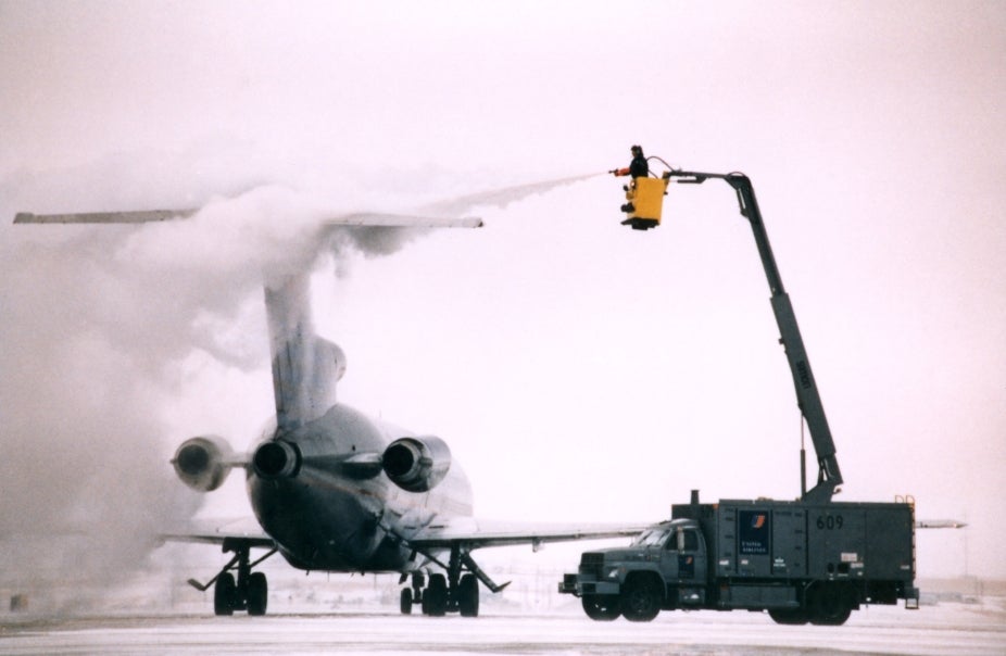 A plane parked on a tarmac being deiced