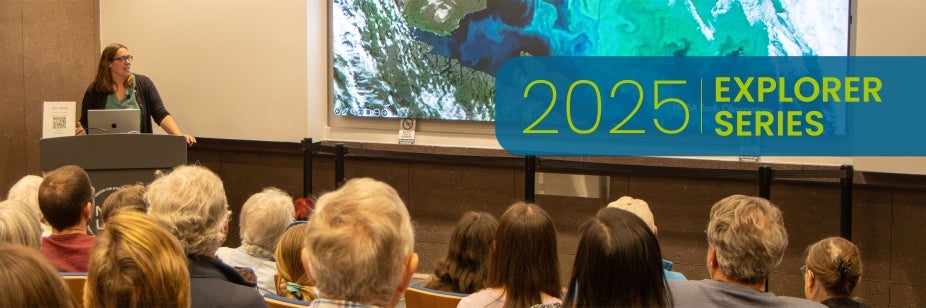 A woman stands at a lectern in front of an audience and delivers a science talk