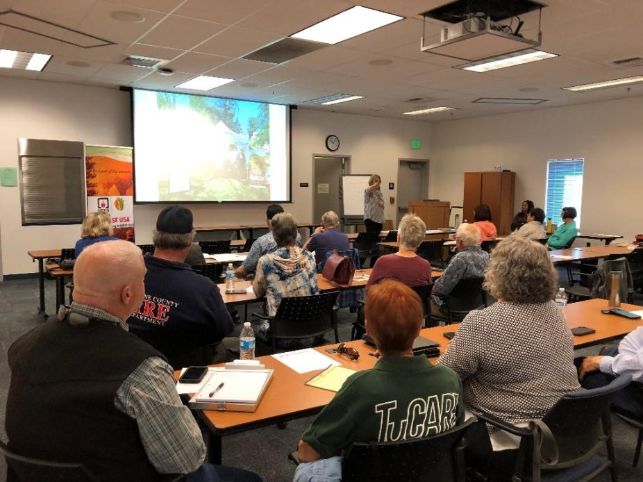 A group of people watch a presentation.