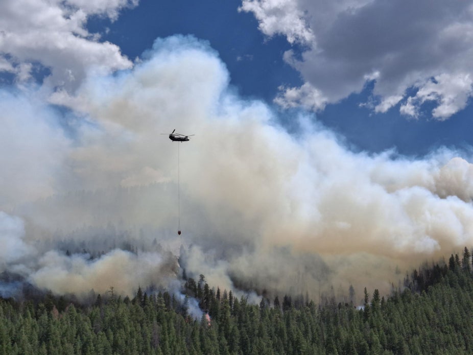 A helicopter fighting a forest fire with smoke in the background