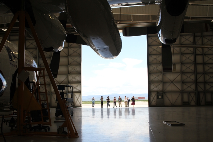 Students pass by the aircraft hangar with an NCAR plane in the foreground