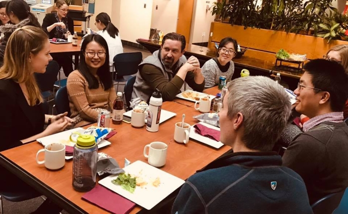 Postdocs gather around a table to chat and eat