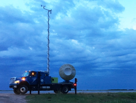A Doppler on Wheels (DOW) sits in the foreground with an overcast sky in the background
