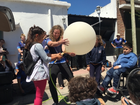 A scientist works with students to inflate a weather balloon
