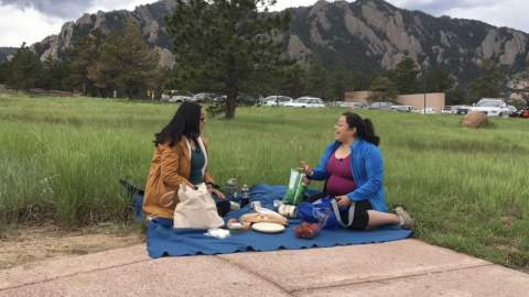Two Latina scientists have a picnic with mountains in the background