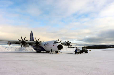 A C-130 research aircraft sits on a snowy tarmac.