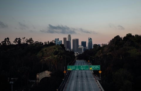 An empty highway with a city in the distance and clear skies