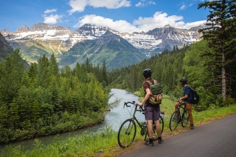 Two mountain bikers stop on a road to look at the mountain vista