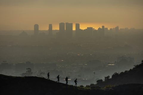Hikers silhouetted against a smoggy city skyline