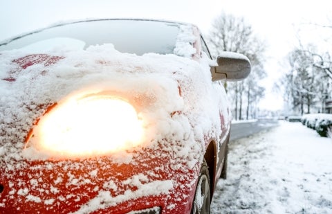 Cloe up on a car's front end covered in wet snow.