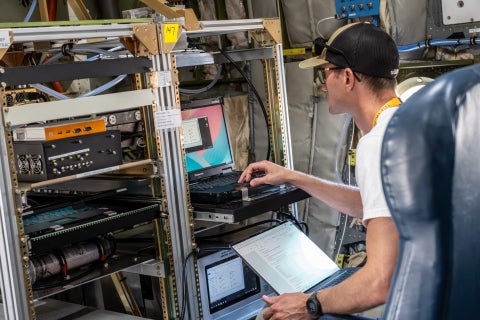 A scientist checks data on a computer attached to an instrument rack in the NSF NCAR C-130