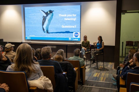 Two scientists sit at the front of an auditorium and answer questions from the audience.
