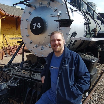 Photo of John Ferrell posing in front of a train