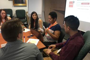 A group of diverse students meet around a table to talk during a meeting.